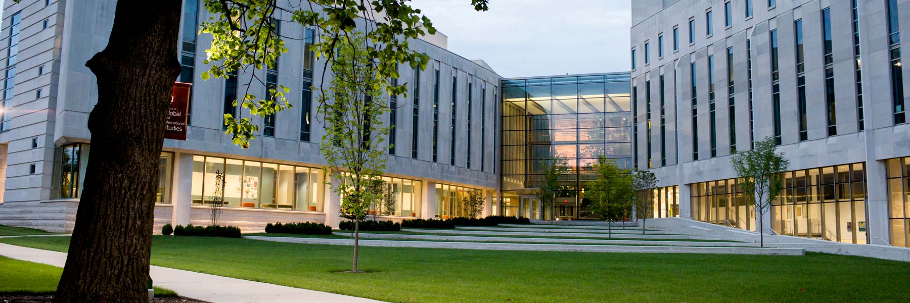 View of the Hamilton Lugar School of Global and International Studies building at dusk with the main public hallways lit a soft yellow from inside.