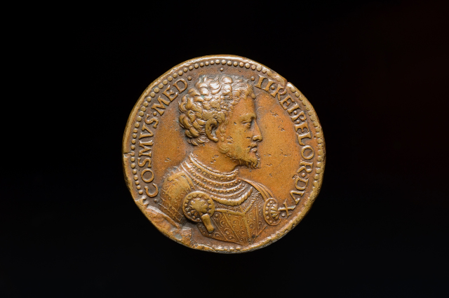 A round bronze medal featuring a portrait in profile of a man in armor. His hair is curly and his armor is decorated with circular additions.