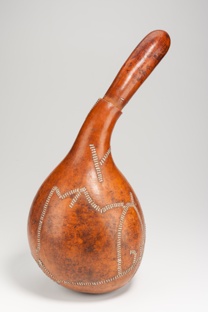 A gourd container with a wide body and long thin neck and lid. The lid fits into the neck of the container. There are pieces of aluminum used for repairs in several areas of the body.