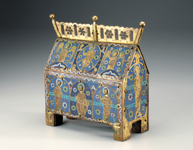 A box-like container on four legs with a triangular, gable-shaped top. Eight figures with protruding heads and halos are pictured on the sides. Predominant colors are blue, gold, and white.